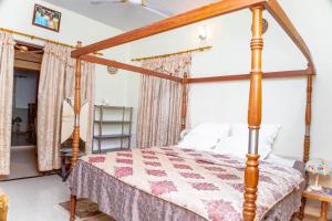 a bedroom with a canopy bed in a room at Art and Leisure-EB Hotel in Takoradi