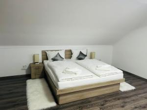 - un lit avec des draps et des oreillers blancs dans une chambre dans l'établissement Casa Potcovarului, à Drăguş