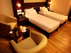 een hotelkamer met 2 bedden en een stoel bij SUNFLOWER HOTEL in Mysore