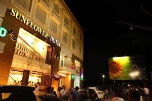 een menigte mensen die 's nachts buiten een gebouw staan bij SUNFLOWER HOTEL in Mysore
