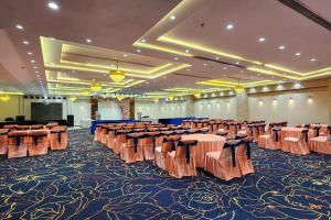 un salón de banquetes con filas de mesas y sillas en Hotel Mandakini Royale, en Kānpur
