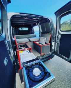 a van with its doors open with a laptop inside at Electric Minicamper blue in Askøy