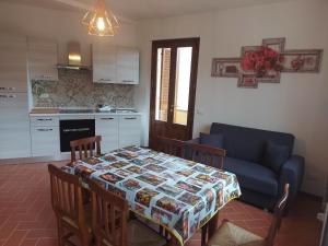 een woonkamer met een tafel en een bank en een keuken bij San Rocco Appartamenti 2 - Appartamento IL CASTAGNO in Asciano Pisano