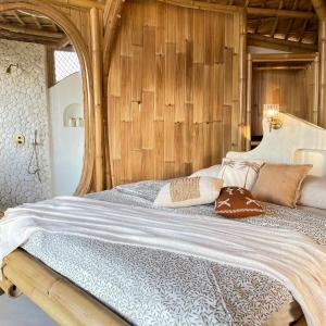 a bedroom with a large bed with wooden walls at Camanta Penida - Adult Only in Nusa Penida