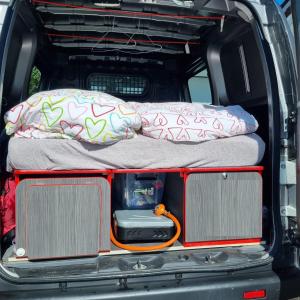 uma cama na parte de trás de uma carrinha com duas almofadas em Electric Minicamper blue em Askøy