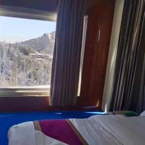 1 dormitorio con ventana y vistas a la montaña en PinnacleHouse kanatal Uttarakhand, en Kanatal