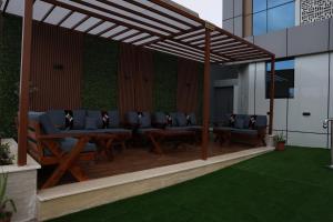 eine Pergola mit Stühlen und Tischen auf einer Terrasse in der Unterkunft جوهرة دومة الجندل للشقق المخدومة Jawharat Dumat Serviced Apartments in Dawmat al Jandal