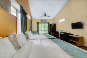 a hotel room with four beds and a television at Amazinn Villa in Lonavala