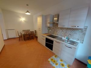 a kitchen with white cabinets and a table with a dining room at San Rocco appartamenti - Appartamento LA VITE in Asciano Pisano