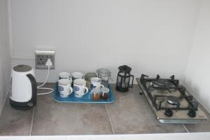 a kitchen counter with a stove and some cups on a tray at House of 2 Oceans in Agulhas