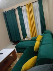 a living room with a green couch with yellow pillows at Embu Paradise 1 bedroom AirBNB in Embu