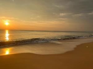 - un coucher de soleil sur une plage donnant sur l'océan dans l'établissement Blue Wave Beach Villa, à Ambalangoda