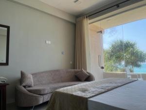- une chambre avec un lit, un canapé et une fenêtre dans l'établissement Blue Wave Beach Villa, à Ambalangoda