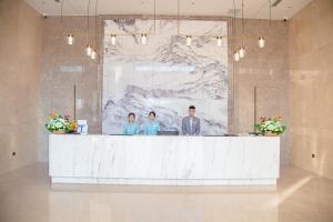 3 Personen stehen hinter einem Tresen in einer Lobby in der Unterkunft LC International Hotel 