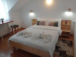 a bedroom with a large white bed with a bow on it at Casa Popa in Gura Humorului