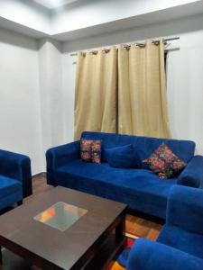uma sala de estar com um sofá azul e uma mesa de centro em Pine Heights Luxury Apartment em Islamabad