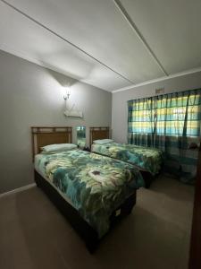 Un dormitorio con dos camas y dos ventanas. en Apt 66 Eden Wilds Umtamvuna Getaway, en Port Edward
