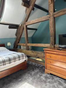 a bedroom with a bed and a dresser with a tv at Auberge du Manet in Montigny-le-Bretonneux