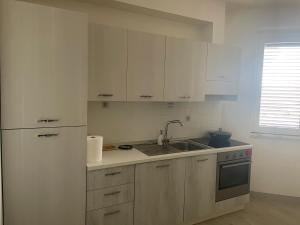 a kitchen with white cabinets and a sink and a refrigerator at Residence Verde Mare in Massignano
