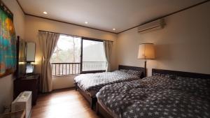 Private hot-spring Villa in Kusatsu في كوساتسو: غرفة نوم بسريرين ونافذة