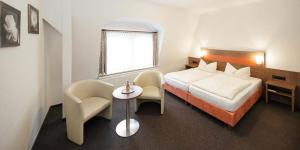 ein Hotelzimmer mit einem Bett und einem Tisch und Stühlen in der Unterkunft Hotel Gasthof Zur Post in Cuxhaven