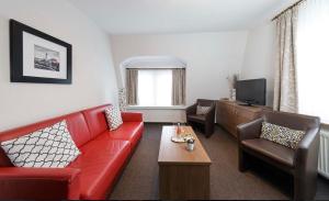 ein Wohnzimmer mit einem roten Sofa und einem Fernseher in der Unterkunft Hotel Gasthof Zur Post in Cuxhaven