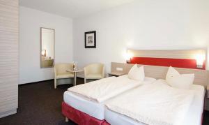 Un dormitorio con una gran cama blanca y una mesa en Hotel Gasthof Zur Post, en Cuxhaven
