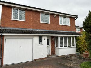 a red brick house with a white garage at Spacious family home in Malins Lee