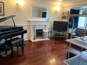 a living room with a piano and a television at Spacious family home in Malins Lee