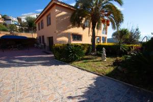 a house with a palm tree next to a sidewalk at Catalunya Casas Heart of Costa Brava and 2,7km to beach in Blanes