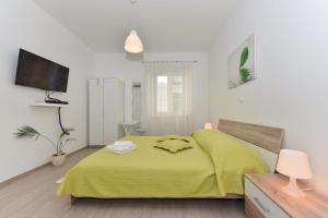 a bedroom with a bed with a yellow blanket at Rooms Old Town in Zadar