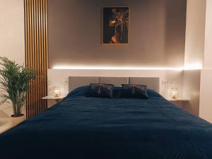 a bedroom with a blue bed with two lamps at Adula - pokoje i apartamenty in Janów Lubelski