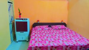 um quarto com uma cama com lençóis cor-de-rosa e uma televisão em Mahavir Home Stay em Ujaim