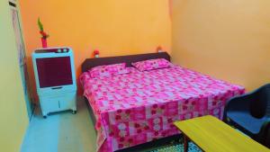 ein Schlafzimmer mit einem rosa Bett und einem kleinen Kühlschrank in der Unterkunft Mahavir Home Stay in Ujjain