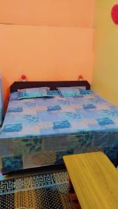 Schlafzimmer mit einem Bett mit blauer Bettwäsche und einem Tisch in der Unterkunft Mahavir Home Stay in Ujjain