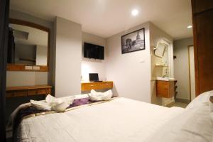 L Hotel في بانكوك: غرفة نوم مع سرير أبيض كبير مع مرآة