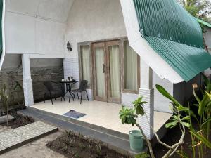 um alpendre de uma casa com uma mesa e cadeiras em Rumah Tiga Gili #Lumbung em Gili Air