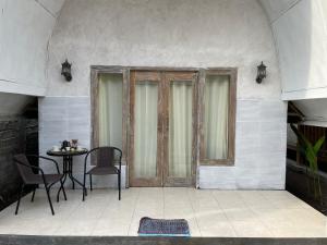 een patio met een tafel en stoelen en een deur bij Rumah Tiga Gili #Lumbung in Gili Air