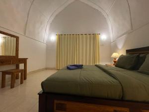 1 dormitorio con cama, mesa y ventana en Rumah Tiga Gili #Lumbung en Gili Air
