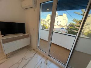 a living room with a tv and a large window at MAGNÍFICO ADOSADO CERCA DEL MAR in Canet de Berenguer