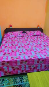 ein rosa Bett mit rosa Bettwäsche und rosa Kissen in der Unterkunft Mahavir Home Stay in Ujjain