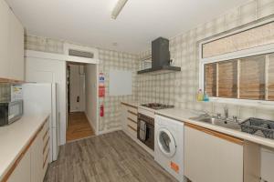 een keuken met een wasmachine en een wastafel bij Cosy 4 bedrooms house near Central London, O2, London city airport and Excel in Plumstead
