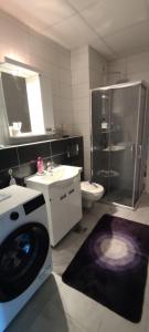 een badkamer met een douche, een toilet en een wastafel bij Apartman 022 in Smederevska Palanka