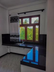 a kitchen with a window and a black counter top at River Relax Villa in Ahangama