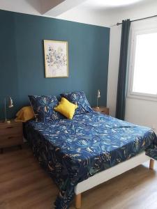 勒普拉代Superbe appartement au cœur du village的卧室内的一张床铺,卧室内有蓝色的墙壁