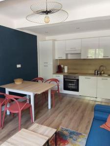 勒普拉代Superbe appartement au cœur du village的一间带桌椅的厨房和一间带白色橱柜的厨房