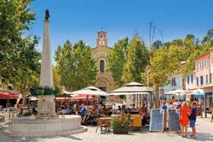 勒普拉代Superbe appartement au cœur du village的街道中央的喷泉,有钟楼 更多2张照片