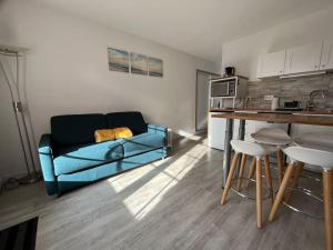 sala de estar con sofá azul y cocina en Le Refuge Marin, en Courseulles-sur-Mer