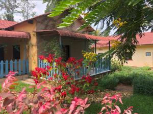 ein Haus mit einem blauen Zaun und roten Blumen in der Unterkunft Lakeside Fish Farm in Bugesera