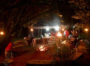 a group of people sitting around a fire at night at Lakeside Fish Farm in Bugesera